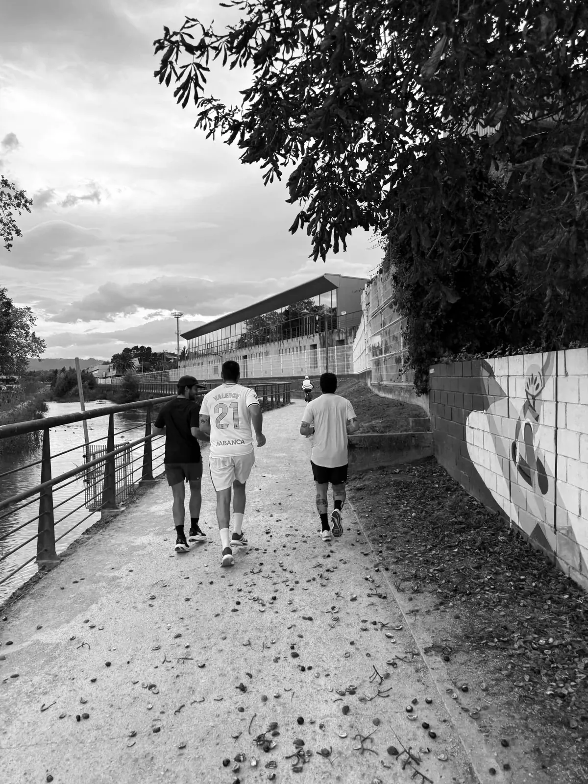 Three Resizes teammates running together along a riverside path, seen from behind.